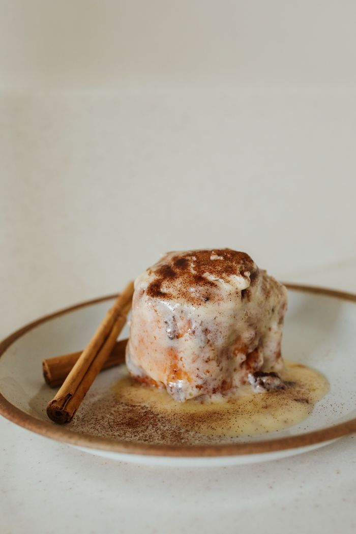 A cinnamon bun with a light vanilla glaze on a ceramic plate.